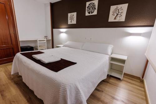 a bedroom with a white bed with two towels on it at Hostal Gran Vía in Pinto