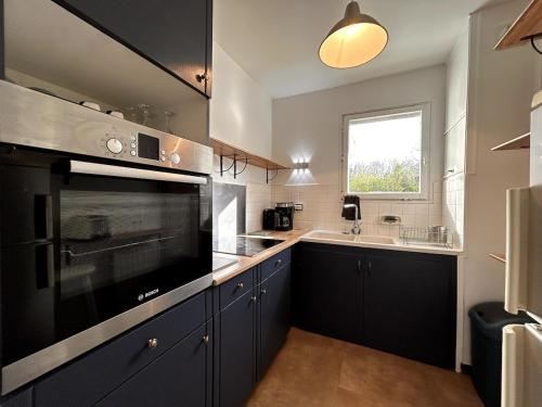 une cuisine avec des armoires bleues, un évier et une fenêtre dans l'établissement Le cocon des Maraîchers & Parking et 400 m from train station, à Avon