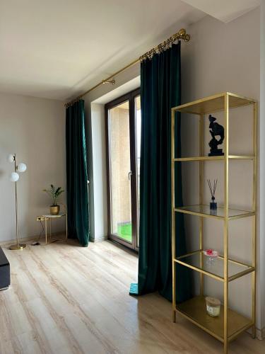 a living room with green curtains and a book shelf at Opera Apartment Centrum PKS PKP in Częstochowa