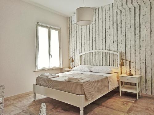 a white bedroom with a bed and a window at Colleoni 19 in Civitanova Marche