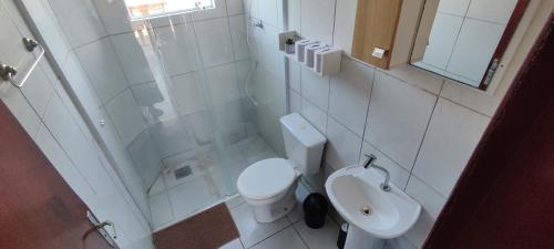 a white bathroom with a toilet and a shower at Aconchego na Praia em Palhoça in Palhoça