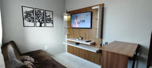 a living room with a couch and a television on a wall at Aconchego na Praia em Palhoça in Palhoça