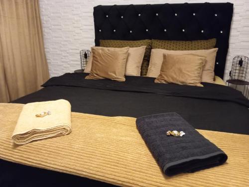 a bed with two towels and two slippers on it at Black Diamond Lux - deluxe riverside apartment in Senta