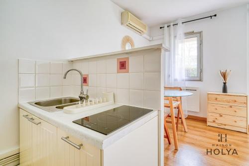 une cuisine blanche avec un évier et une table dans l'établissement Le Calme aux portes de Paris - 400B, à Rueil-Malmaison