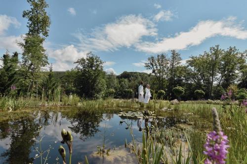 a bride and groom standing in front of a pond at Schlosspark Mauerbach - Adults only in Mauerbach
