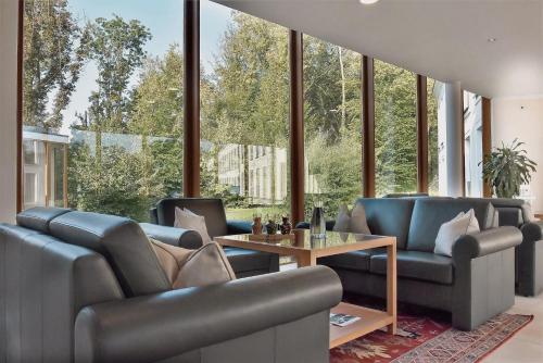 a living room with leather furniture and large windows at Schlosspark Mauerbach - Adults only in Mauerbach