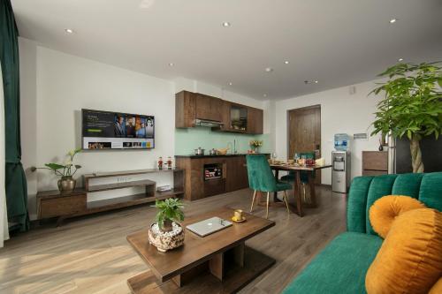 a living room with a green couch and a kitchen at Bloom in Hanoi - The Residences in Hanoi
