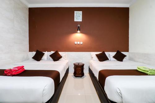 two beds in a hotel room with a red bag on them at Hotel Safara Yogyakarta in Yogyakarta