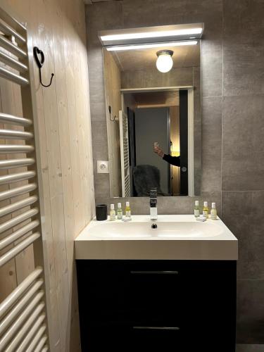 La salle de bains est pourvue d'un lavabo et d'une personne dans un miroir. dans l'établissement Light spacious, recently refurbished Studio near to Courchevel, à Courchevel