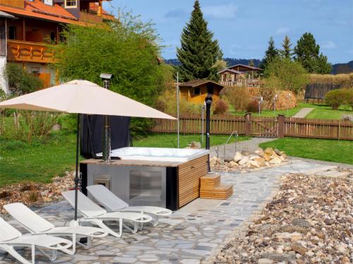 a patio with a hot tub and chairs and an umbrella at Birkholmhof in Bärnau