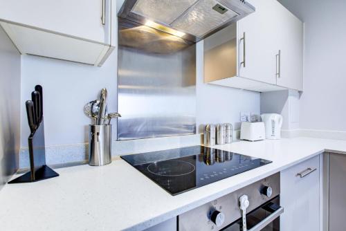 a kitchen with white cabinets and a stove top oven at 2 BR Flat 6 Mins From Heathrow Airport Flat 41 in Harmondsworth