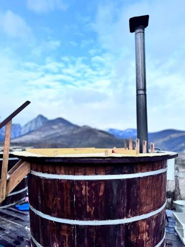 a barrel with a chimney with mountains in the background at Pensiunea Bodrogeni in Poiana Aiudului