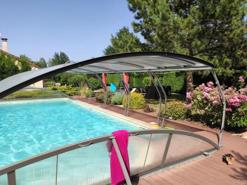 une piscine avec un auvent au-dessus d'une piscine dans l'établissement Rêve d'eau et de Nature, à Burgnac