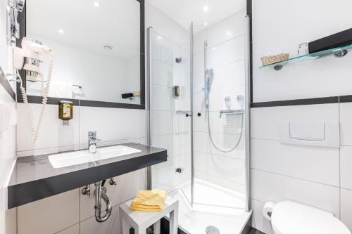 a white bathroom with a sink and a shower at Strandhotel Löchnerhaus in Reichenau