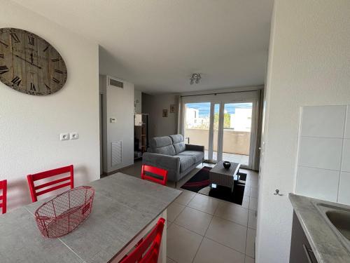 d'une cuisine et d'un salon avec une horloge murale. dans l'établissement Appartement cosy à Valras-Plage 5 min à pied de la mer Climatisé 2 chambres Terrasse, à Sérignan