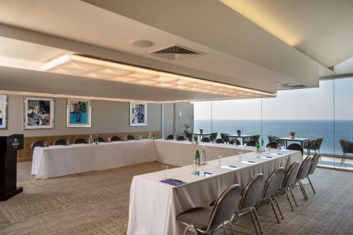 a conference room with tables and chairs and the ocean at The Vista At Hilton Tel Aviv in Tel Aviv