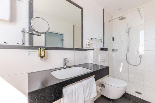 a white bathroom with a sink and a toilet at Strandhotel Löchnerhaus in Reichenau