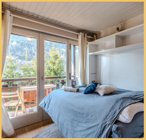 une chambre avec un grand lit et un balcon dans l'établissement La Grange Neuve I T1 I Les Gets, aux Gets