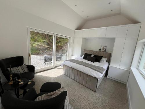 a bedroom with a bed and chairs and a window at River Cottage Retreat Hideaway Sauna Sligo Leitrim in Sligo