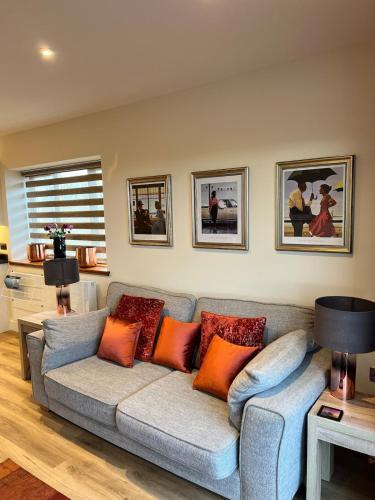 a living room with a gray couch with orange pillows at Dalchalm Hideaway in Brora