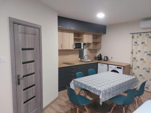 a kitchen with a table and blue chairs in a room at Forest Apartman in Nyíregyháza