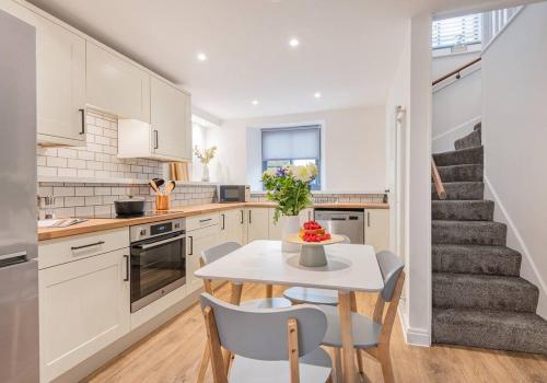 eine Küche mit einem Tisch und Stühlen sowie eine Treppe in der Unterkunft Carpenters Cottage - The Lakes! in Kendal