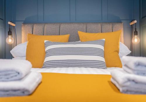 Bett mit gelben und weißen Kissen und Handtüchern in der Unterkunft Carpenters Cottage - The Lakes! in Kendal