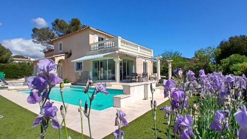 une maison avec des fleurs violettes en face d'une piscine dans l'établissement Villa Iris, climatisée avec 4 chambres et piscine à Boulouris sur Mer, à Saint-Raphaël