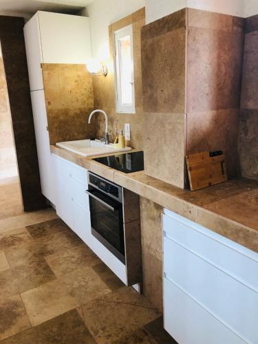 une cuisine avec des armoires blanches et un évier dans l'établissement Charmant studio, à Saint-Tropez