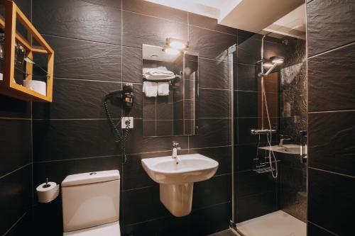 a black tiled bathroom with a sink and a toilet at Hotel Zaragoza Plaza in Donostia-San Sebastián