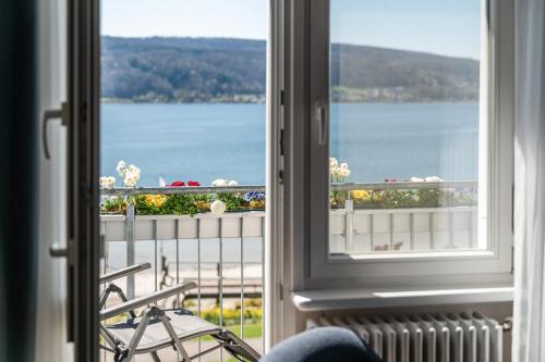 a room with a window with a view of the water at Strandhotel Löchnerhaus in Reichenau