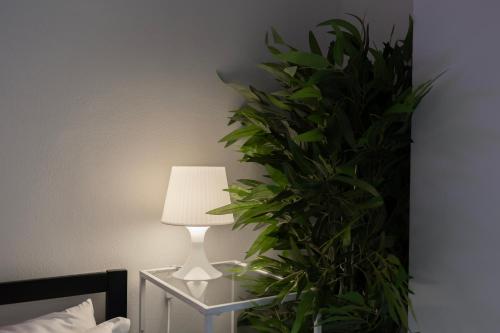a lamp on a night stand next to a plant at Flora 57 - Splendido Loft nel Cuore dei Navigli in Milan