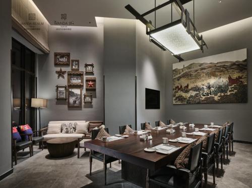 a dining room with a long table and a couch at Wanda Realm Yan'an in Yan'an