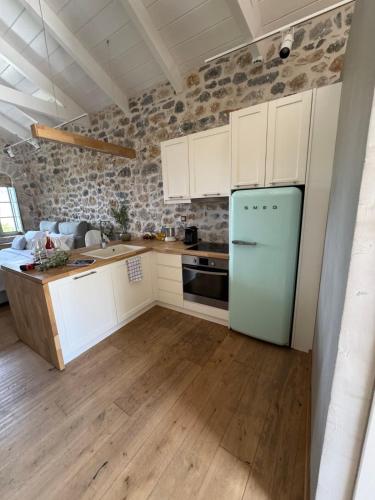 a kitchen with white cabinets and a blue refrigerator at Mani Stone Studios in Oítilon