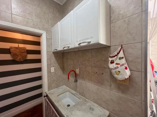 a small bathroom with a sink and white cabinets at Vista Lateral Mar Fique No Melhor Lugar da Praia in São Vicente