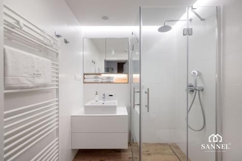 un bagno bianco con lavandino e doccia di Apartament Premium Baltic View-Pinea Apartments Pobierowo-morze na wyciągnięcie ręki!-dostęp do strefy basenów,saun i jacuzzi-SANNEL Apartments for rent a Pobierowo