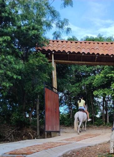a person riding a white horse under a pavilion at El Eden Glamping cabañas Girardot in Girardot