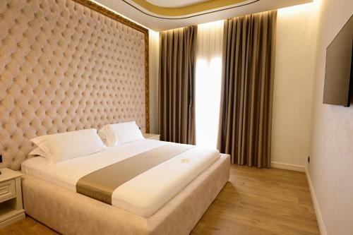 a bedroom with a large bed and a large window at King & Queen Boutique Hotel in Fier