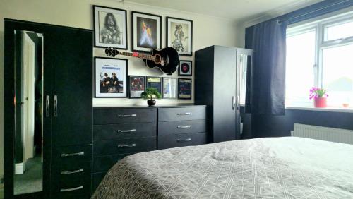 a bedroom with a bed and a guitar on a wall at Detached Homestay - Super, King & Double Rooms - Leyland, Preston, Chorley, Lancashire in Leyland