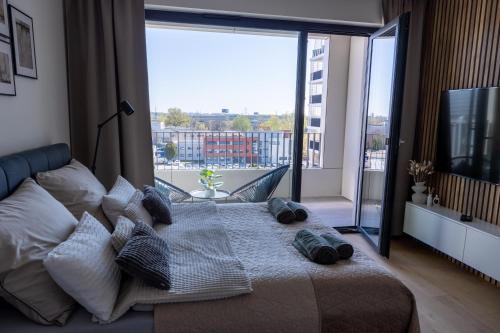 ein Schlafzimmer mit einem Bett mit Kissen und einem großen Fenster in der Unterkunft Apartmán LEON - FREE GARAGE PARKING in Bratislava