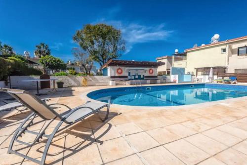 a swimming pool with two lounge chairs next to a house at Akamas Sunset Bohemian Chic Apartment by ONE VILLAS in Polis Chrysochous