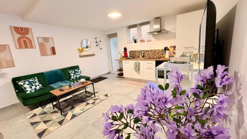 a living room with a green couch and purple flowers at Cocon urbain , bel appartement entièrement équipé, entrée privée, parking in Wittenheim