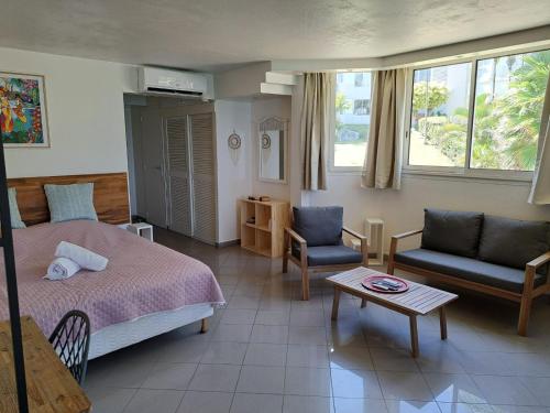 a bedroom with a bed and a couch and a table at F1 vue mer, accès plage, en centre-ville in Le Gosier