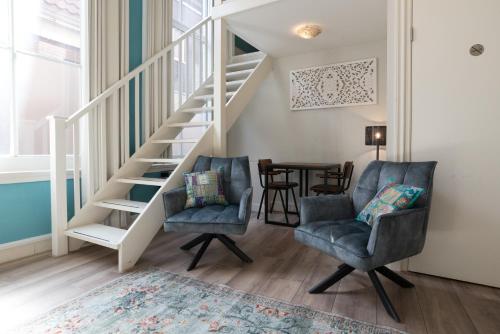 a living room with two chairs and a staircase at 1001 Nights Boutique Lofts in Haarlem