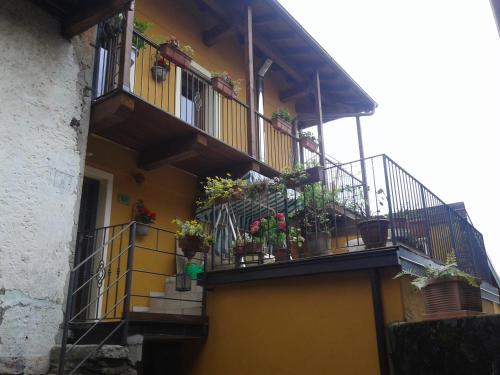 a yellow building with potted plants on the balconies at B&B Il Castello Lago Maggiore con TERRAZZA in Cossogno