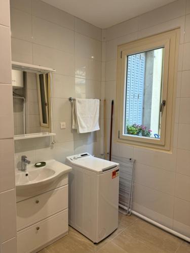 une salle de bain blanche avec un lavabo et une fenêtre dans l'établissement Appartement meublé tout confort, à Chalon-sur-Saône