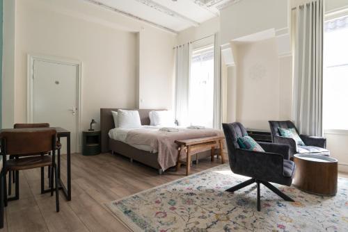 a bedroom with a bed and two chairs and a table at 1001 Nights Boutique Lofts in Haarlem