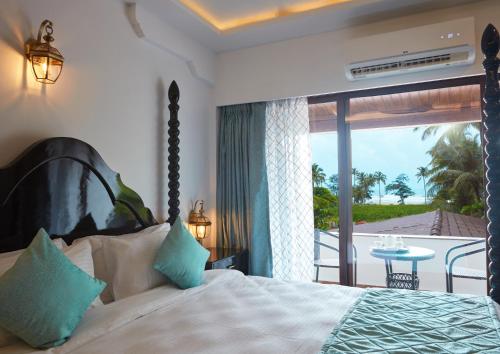 a bedroom with a bed with a view of a balcony at Sea Queen Beach Resort & Spa in Colva