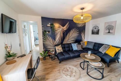 un salon avec un canapé et une table dans l'établissement JUNGLE Appart 2 chambres parking 10min port Honfleur et plage, à Honfleur