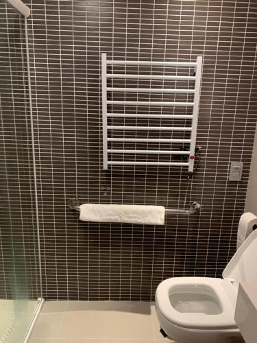 a bathroom with a toilet and a black tiled wall at Stay batel luxo em Curitiba in Curitiba
